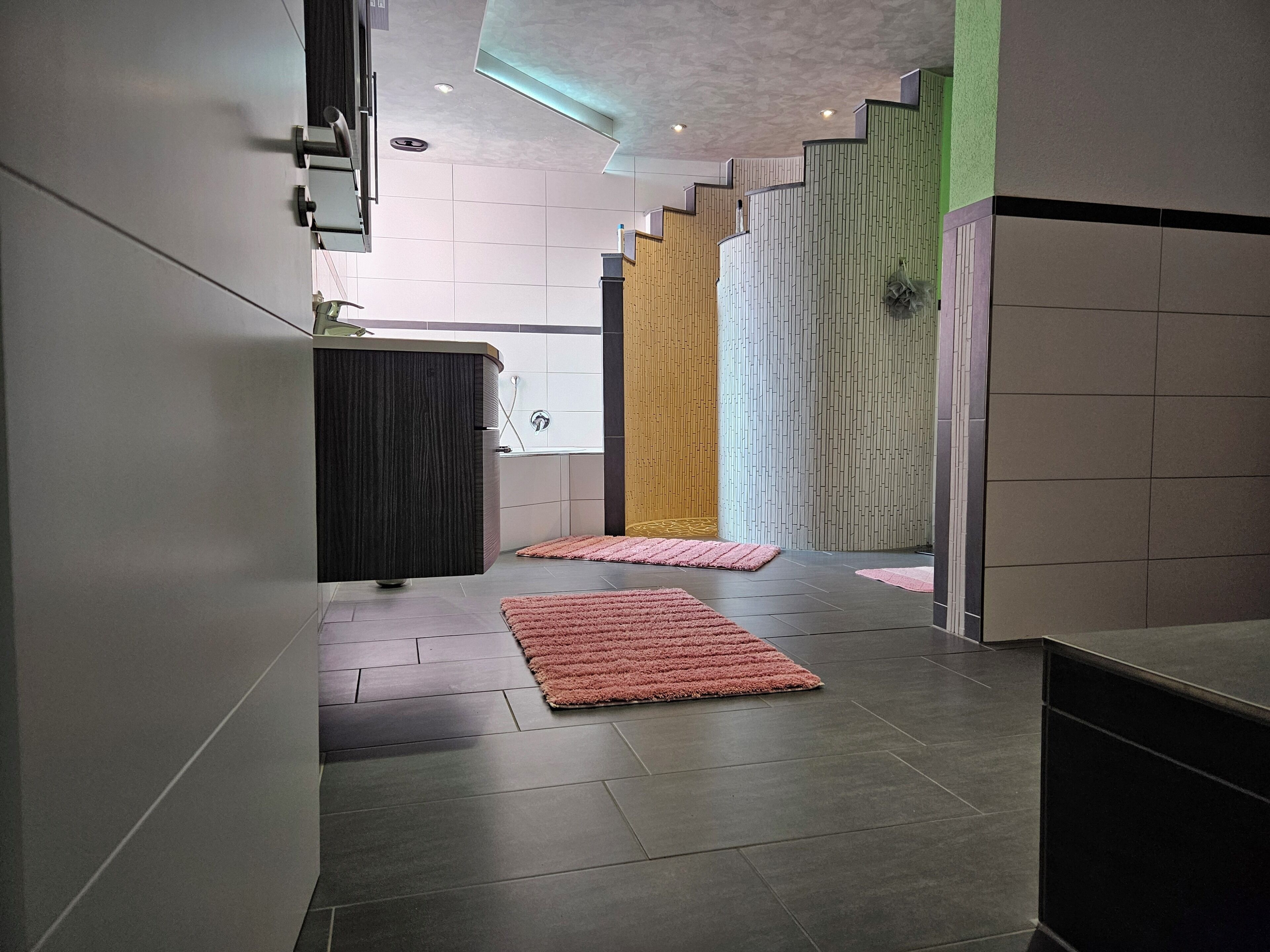 Un interior moderno con una escalera, un armario de madera y un baño con ducha.