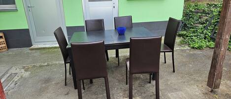 An outdoor dining area with a table and chairs, a door, and a window.