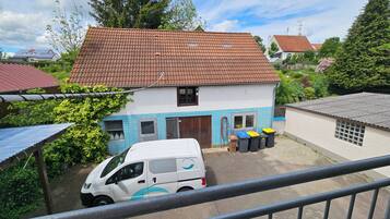 A two-story house with a tiled roof, a white van parked in front, and a blue door.