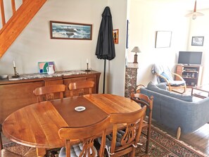 Un comedor con una mesa y sillas de madera, un sofá, un televisor y un cuadro en la pared.