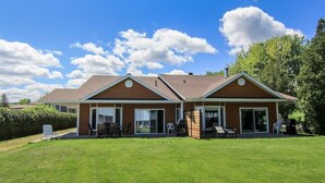 A two-story house with a large lawn, a covered patio, and a garage.