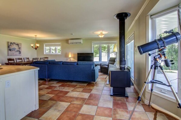 Una sala de estar con un sofá modular, un televisor, una chimenea y un telescopio.