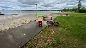 A lakeside park with a paved walkway, benches, and a kayak.