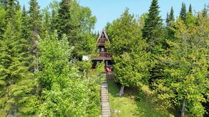 Une cabane en bois, dotée d’un toit triangulaire, entourée d’une forêt dense.