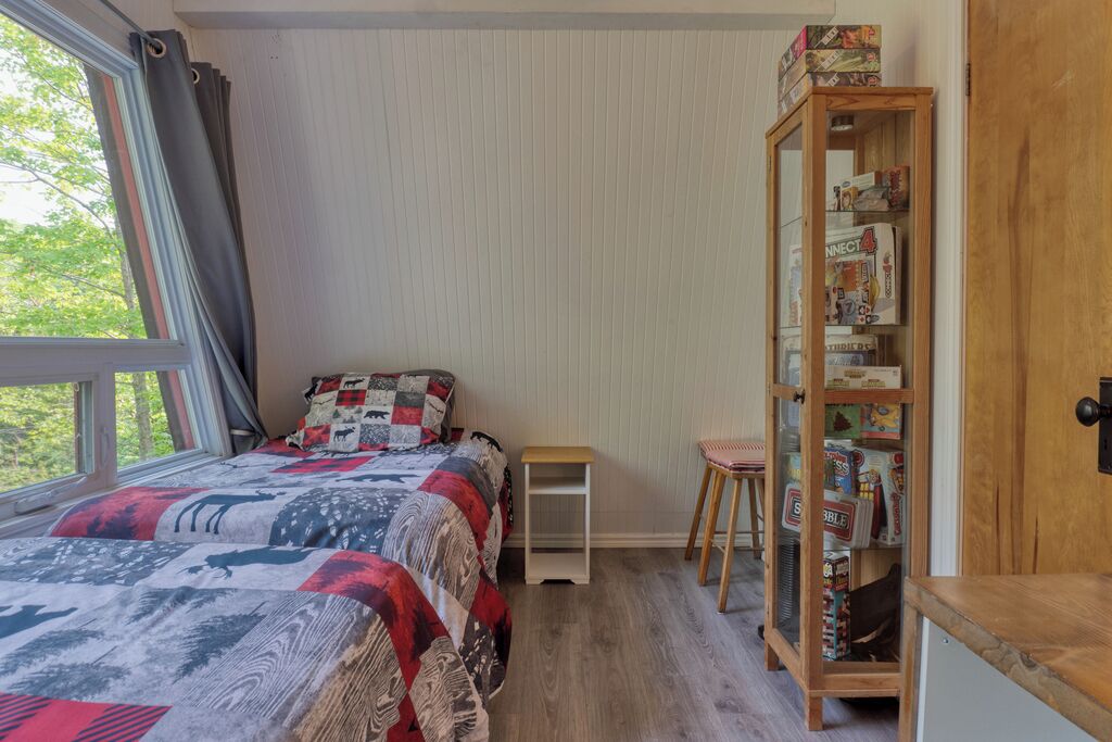 Ein Schlafzimmer mit Bett, einem kleinen Tisch, einem Stuhl und einem Bücherregal.