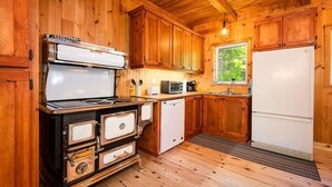 A kitchen with wooden cabinets, a stove, a microwave, and a refrigerator.