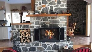Ein gemütliches Wohnzimmer mit Kamin aus Stein, zwei Schaukelstühlen und einem Holztisch.
