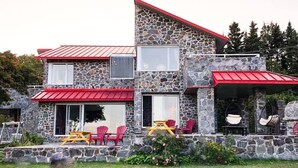 Ein Gebäude aus Stein mit rotem Dach, Außenbestuhlung und Hängestühlen.