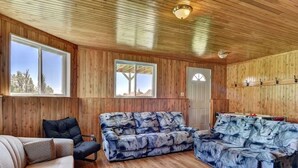 Una stanza con rivestimenti in legno, un divano, una poltrona e soffitto in legno.