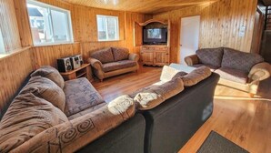 A wooden cabin interior with a sofa set, a television, and a cabinet. - Hôtel à la maison - La Maison Elsa, fleuve et ski (Petite-Rivière-Saint-François)