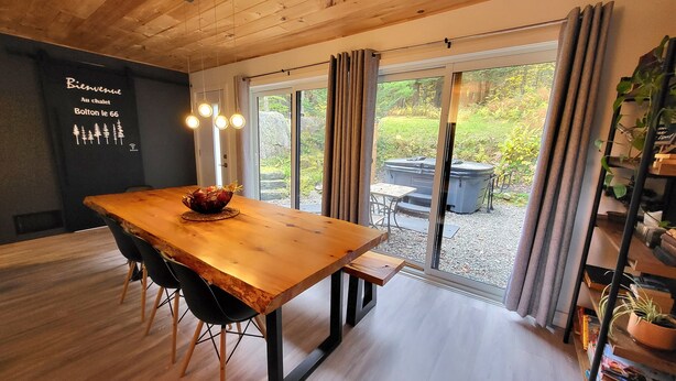 Ein Holztisch mit Stühlen, eine Obstschale und Blick auf eine Whirlpoolanlage und Garten durch große Schiebeglastüren.