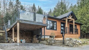 Eine Holzhütte mit Glasbalkon, Holzfassade und Steinuntergrund.