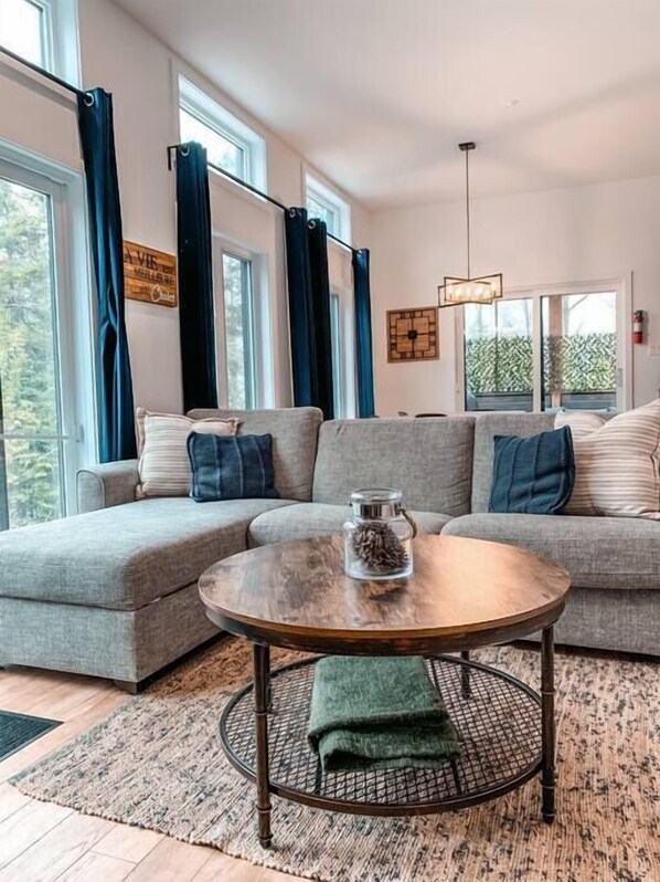 Una sala moderna con un sofá modular, una mesa de centro redonda y vistas al exterior a través de amplios ventanales.