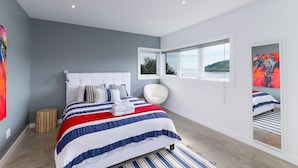 A modern bedroom with a large bed, a chair, and a view of the outdoors through a window. - Hôtel à la maison - Panache, spa et fleuve (Baie-Saint-Paul)