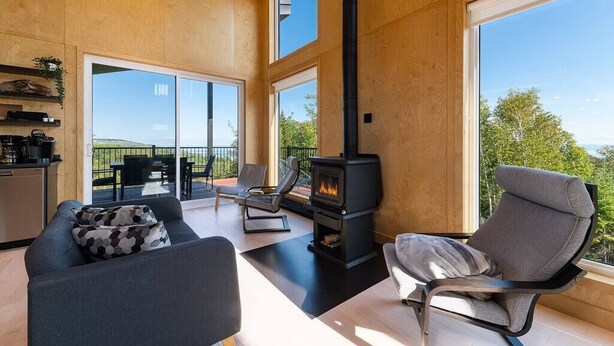 Amplia sala de estar con chimenea moderna, asientos cómodos y ventanas grandes con vistas al exterior.
