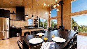 Una cocina moderna con electrodomésticos de acero inoxidable, una mesa de comedor lista para dos personas con platos y vasos, y una revista sobre la mesa.