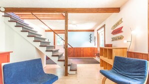 A staircase with wooden railings and a blue carpeted floor. There are two blue chairs and a wooden bench in the room. - Hôtel à la maison - L'Éphémère, Nature et Lac! (Sutton)