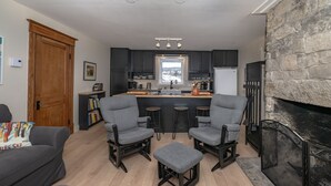 A modern kitchen with dark cabinets, a central island, and a stone fireplace.