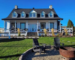 A two-story house with a porch, a fire pit, and outdoor seating.