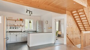 A modern kitchen with white cabinetry, a central island, and a wooden staircase.