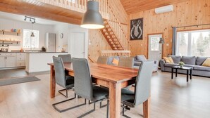 A spacious living area with a wooden dining table and chairs, a sofa, and a staircase leading to an upper level.
