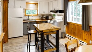 Eine moderne Küche mit weißen Schränken, einem Holztisch und einem Fenster mit Vorhängen.