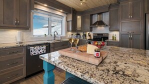 Una cocina moderna con armarios oscuros, encimera de granito y horno empotrado.