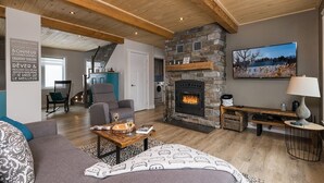 Una sala de estar acogedora con chimenea de piedra, un sofá confortable y un televisor montado en la pared.