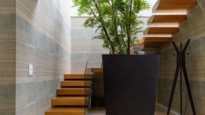 Una escalera moderna con escalones de madera y barandas de vidrio, que conduce a una estructura oscura y minimalista.