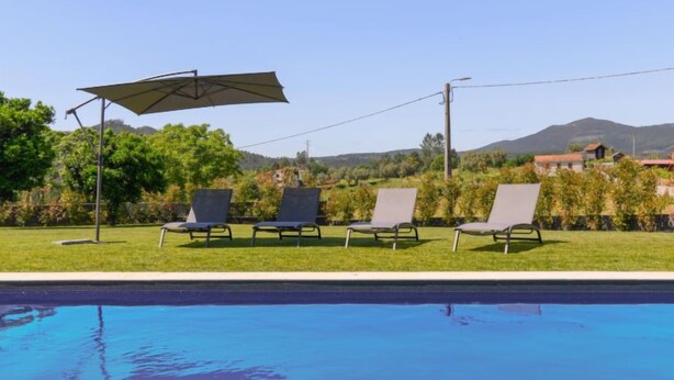 A swimming pool with lounge chairs and an umbrella. - Douro Escape by Interhome (Lomba-Gondomar)