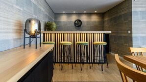 Una cocina moderna con encimera de madera, cuatro taburetes y una barra con un detalle decorativo en la pared.