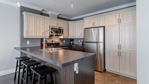 Una cocina moderna con una isla central, electrodomésticos de acero inoxidable y muebles de madera clara.