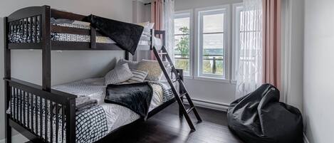Habitación con literas, un sillón de pelota y una ventana con cortinas.