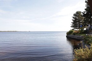 Una tranquilla vista sull'acqua, con una casa sulla destra e una costa in lontananza.