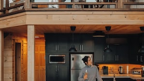 Un loft spacieux avec de hauts plafonds, des poutres apparentes, un balcon agrémenté d’un fauteuil suspendu, une cuisine équipée d’appareils modernes et une grande fenêtre laissant entrer la lumière naturelle.