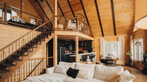 Un vaste espace de vie agrémenté d’un escalier en bois, d’un canapé confortable et d’un coin repas avec une table et des chaises.