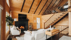 L’intérieur d’un chalet en bois chaleureux et accueillant, avec une cheminée, un escalier et un coin salon confortable.
