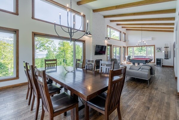 A spacious living area with a large wooden dining table, comfortable seating, and a fireplace.