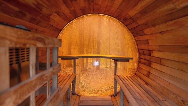 A wooden sauna with benches and a bench in the center.