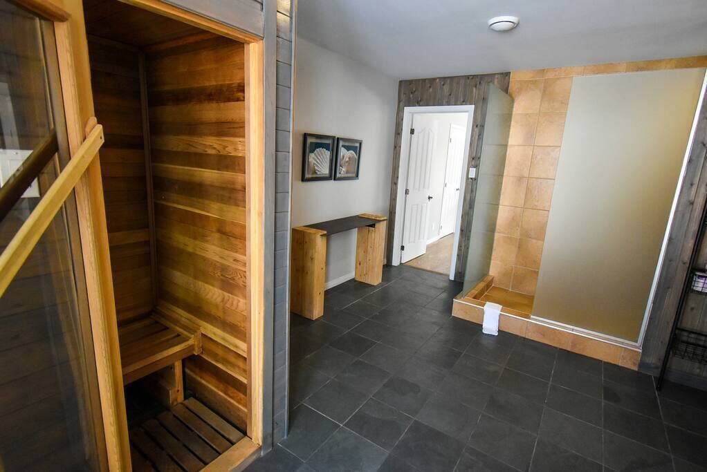 A hallway with a wooden wardrobe, a bench, and a door leading to a bathroom.