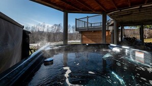 A hot tub under a wooden pergola with a view of a mountain and trees. - Hôtel à la maison - Colombe du Cap, foyer et spa (Baie-Saint-Paul)