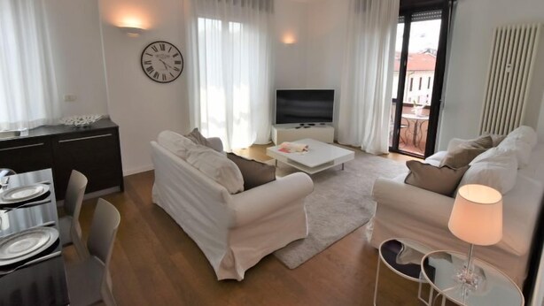 A modern living room with a sofa set, a coffee table, a TV, and a dining area with a table and chairs.