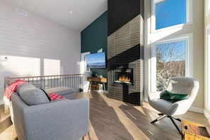 Una sala de estar moderna con chimenea, un sofá, un sillón y un televisor.