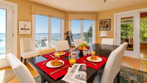 A dining area with a table set for breakfast, overlooking a scenic view. - Hôtel à la maison - Villa du Cap Blanc, spa et Vue (Saint-Irénée)