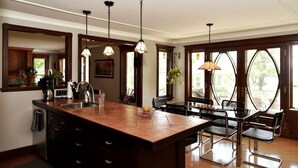 Una cocina con una isla grande, luces colgantes y vistas a través de las ventanas.