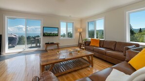 Un salon spacieux avec une table basse en bois, un canapé en cuir et de grandes fenêtres offrant une vue panoramique.