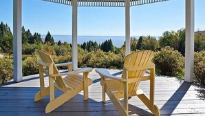 Un belvédère agrémenté de deux fauteuils Adirondack, offrant une vue panoramique sur l’océan et la forêt.