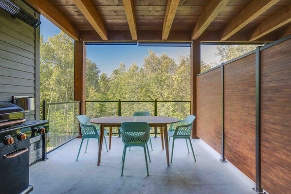 A covered outdoor area with a wooden ceiling, a grill, and a table with chairs. - Hôtel à la maison - Le Rendez-vous ! (Orford)