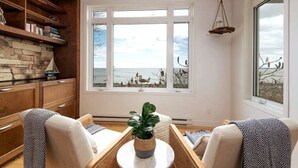 Una sala de estar acogedora con chimenea de piedra, un ventanal con vistas y una lámpara colgante.