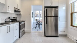 Una cocina moderna con armarios blancos, electrodomésticos de acero inoxidable y vistas a un balcón.